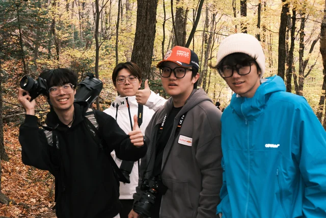 Four friends posing together on an autumn forest trail.